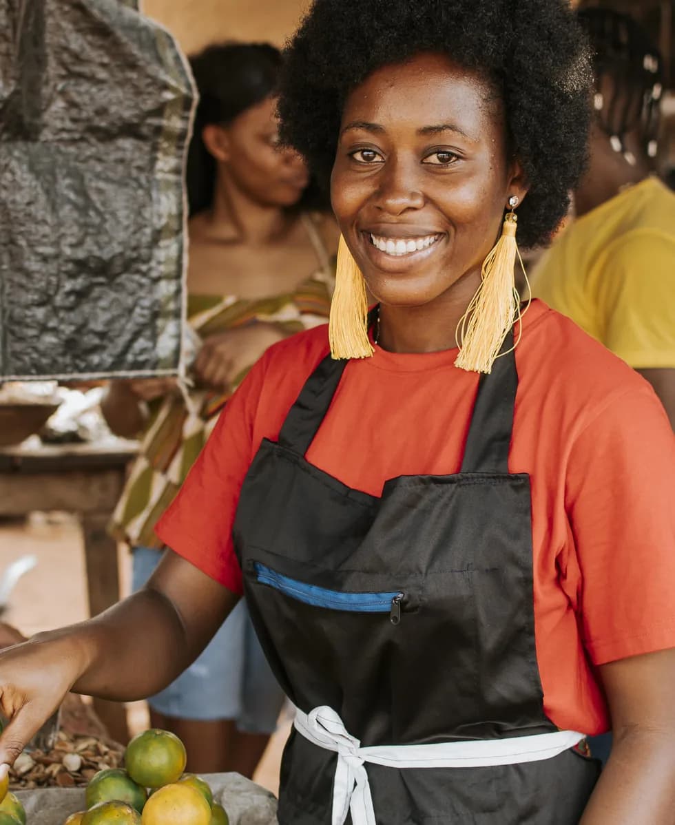 Smiling trader in an apron at her market stall
